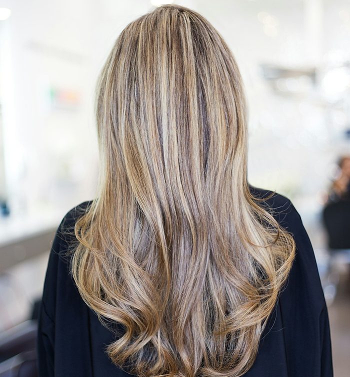 Melena rubia larga con mechas y ondas suaves, vista de espaldas