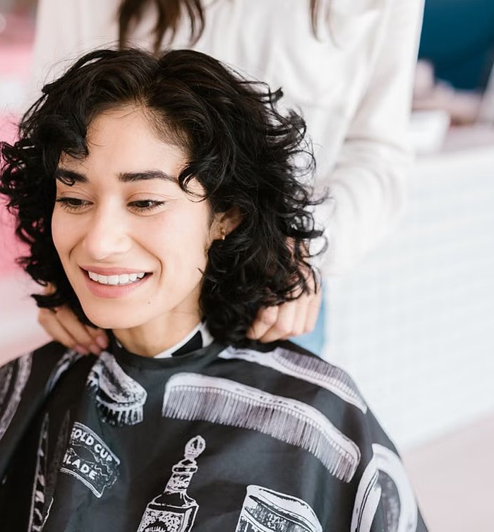 Clienta con corte rizado corto, sonriendo tras el secado