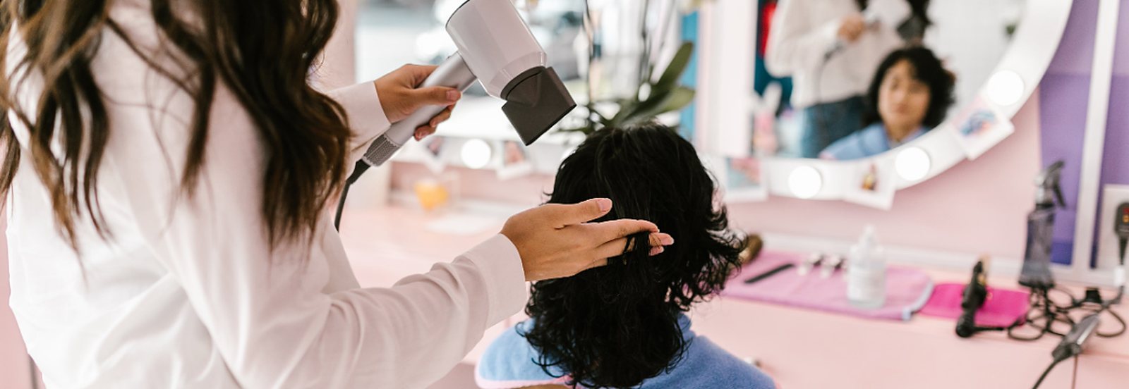 Estilista secando el pelo de una clienta en el salón